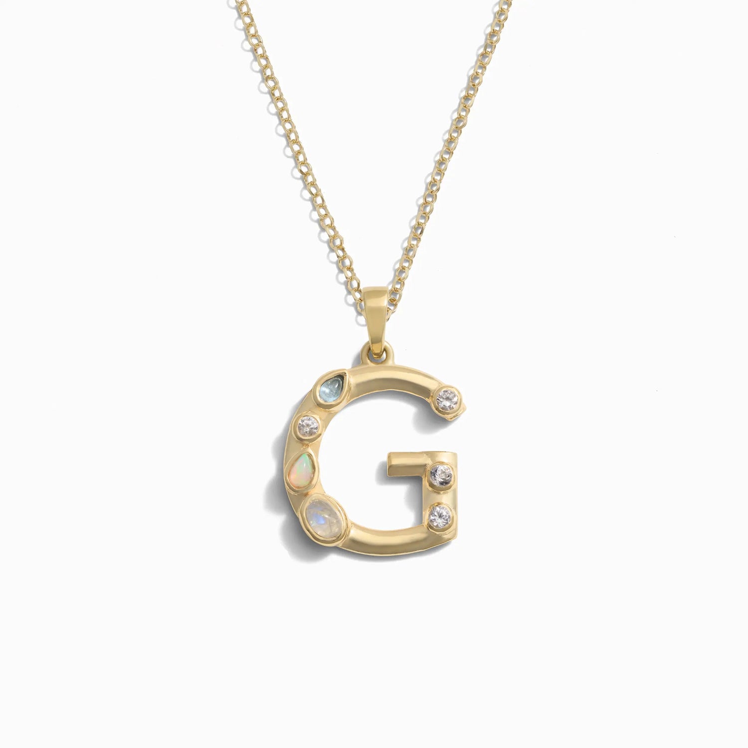 Awe Inspired's Gold Gemstone Initial Necklace features a statement-size pendant shaped like the letter 'G' and adorned with bezel set gemstones.
