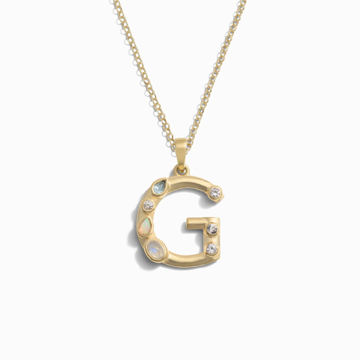Awe Inspired's Gold Gemstone Initial Necklace features a statement-size pendant shaped like the letter 'G' and adorned with bezel set gemstones.