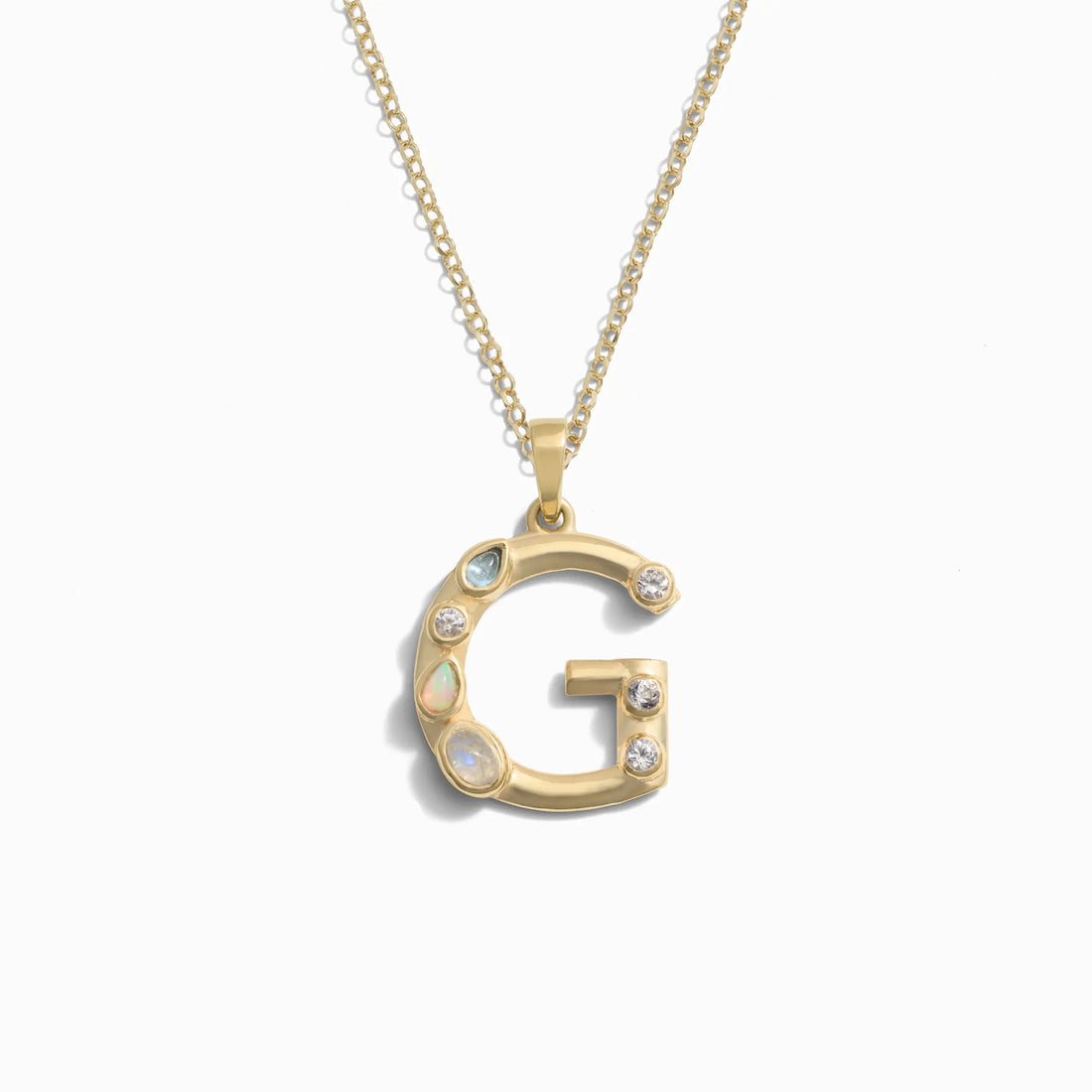 Awe Inspired's Gold Gemstone Initial Necklace features a statement-size pendant shaped like the letter 'G' and adorned with bezel set gemstones.