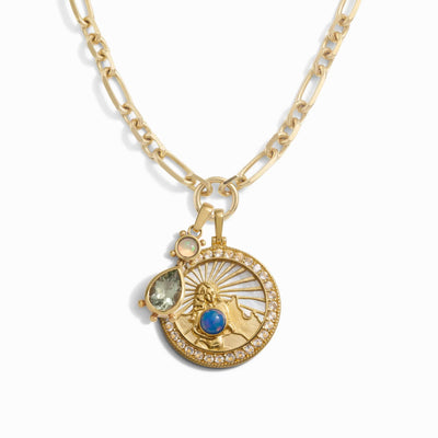 Introducing the Mother Earth Charm Necklace by Awe Inspired: a stunning gold chain necklace adorned with three exquisite pendants—a round pendant featuring a sun and mountain design, a teardrop-shaped blue opal, and a small round iridescent gem.