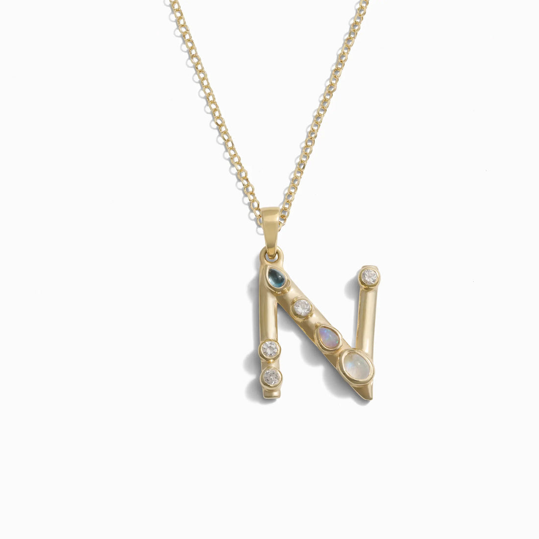 The Gold Gemstone Initial Necklace by Awe Inspired is a stunning piece featuring a statement-size "N" pendant adorned with bezel-set gemstones.
