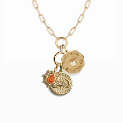 The Cosmic Affirmation Charm Necklace from Awe Inspired features three beautiful pendants: a hexagon inscribed with "Everything I Need is Within Me," a sun-shaped pendant adorned with a red gemstone, and a circular Aura pendant accented with a diamond.