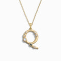 Awe Inspired's Gold Gemstone Initial Necklace features a pendant shaped like the letter "Q," adorned with small, bezel set gemstones.