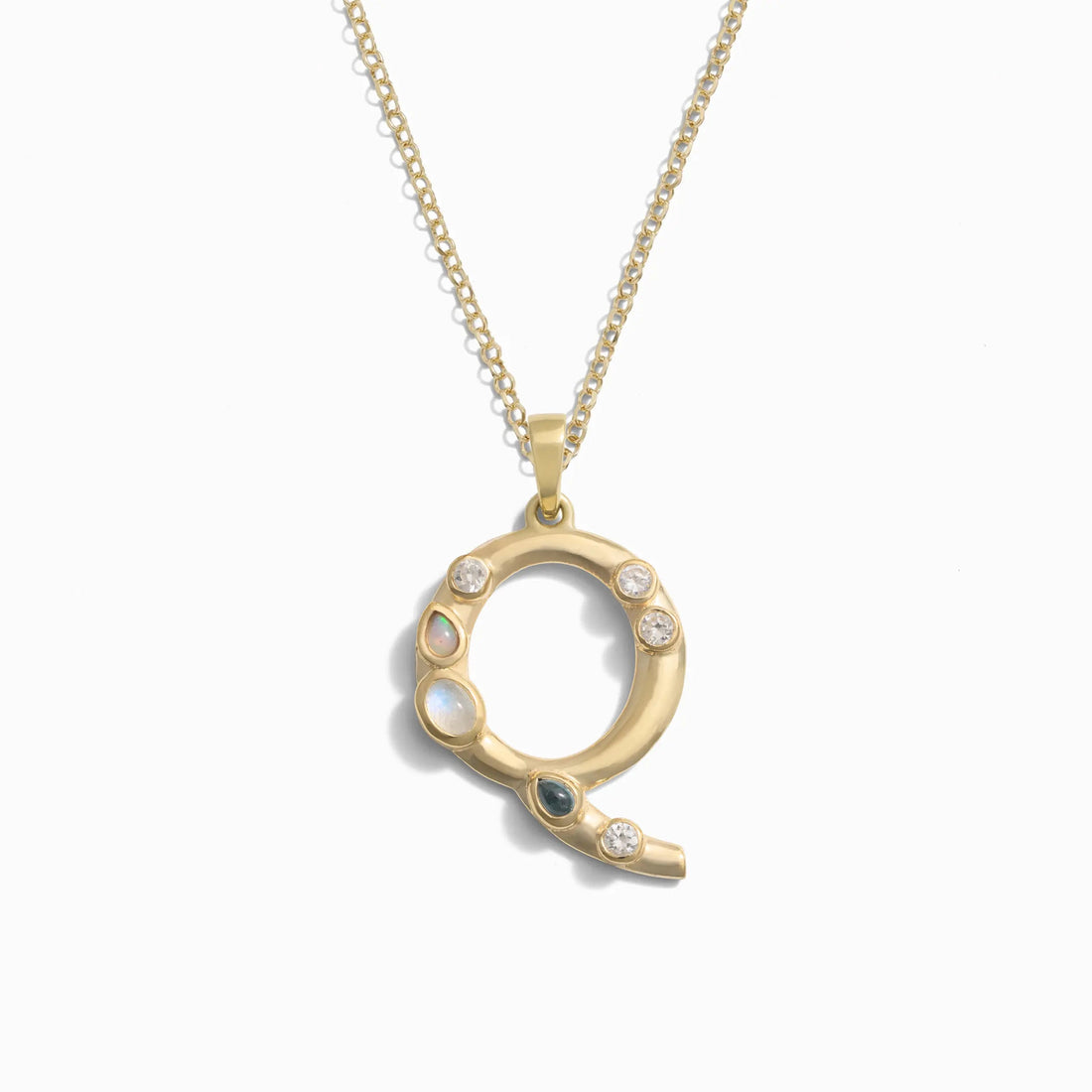 Awe Inspired's Gold Gemstone Initial Necklace features a pendant shaped like the letter "Q," adorned with small, bezel set gemstones.