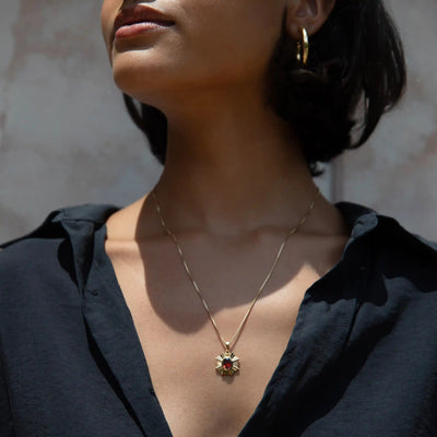 A person wearing the Awe Inspired Aura Pendant, with its gold necklace and striking red stone, enhancing their presence, paired with a sleek black button-up shirt.