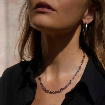 A woman wearing a black shirt and Awe Inspired's Statement Chain Necklace with matching hoop earrings, shown from the neck up.