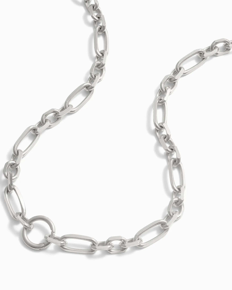 A close-up view of the Statement Single Charm Collector Necklace by Awe Inspired, featuring a silver chain with wide luxe links of varying sizes, displayed on a white background.