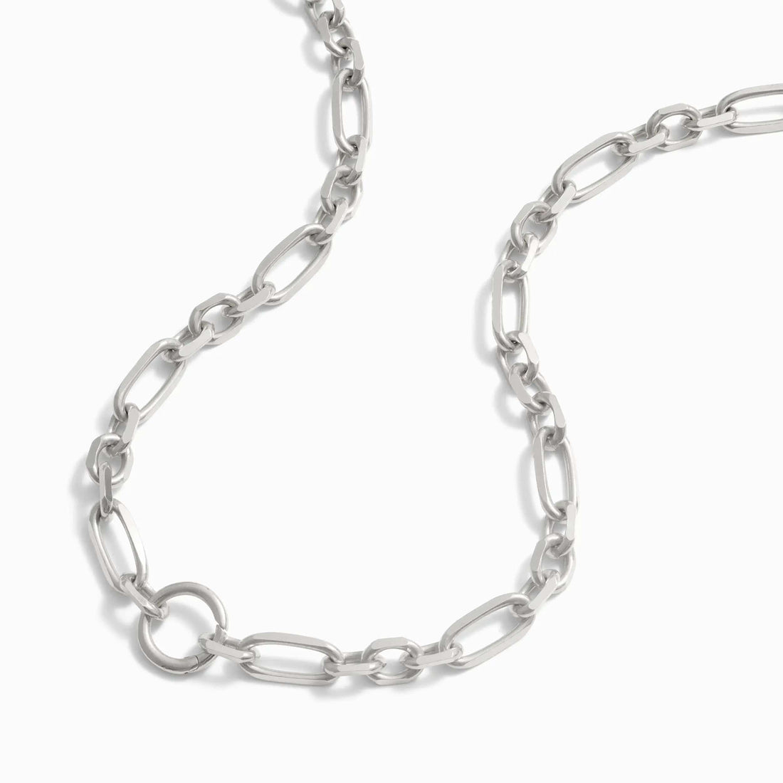 A close-up view of the Statement Single Charm Collector Necklace by Awe Inspired, featuring a silver chain with wide luxe links of varying sizes, displayed on a white background.