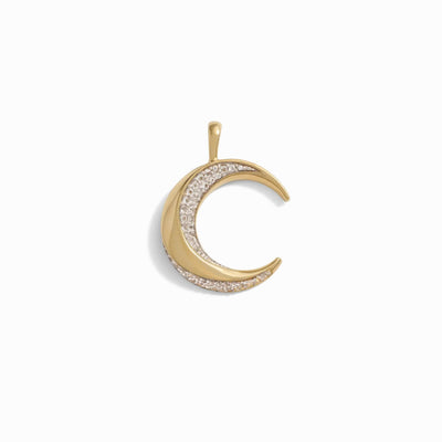 Introducing The Storm Before the Calm Charm Necklace by Awe Inspired: a stunning gold crescent moon-shaped pendant adorned with small clear stones along its inner curve, capturing the essence of the divine feminine, beautifully showcased against a pristine white background.