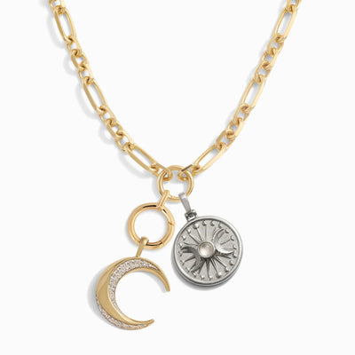 Introducing The Storm Before the Calm Charm Necklace by Awe Inspired, a gold chain necklace featuring two exquisite pendants: a crescent moon adorned with small diamonds and a round, silver sunburst medallion, perfectly capturing the essence of the divine feminine.