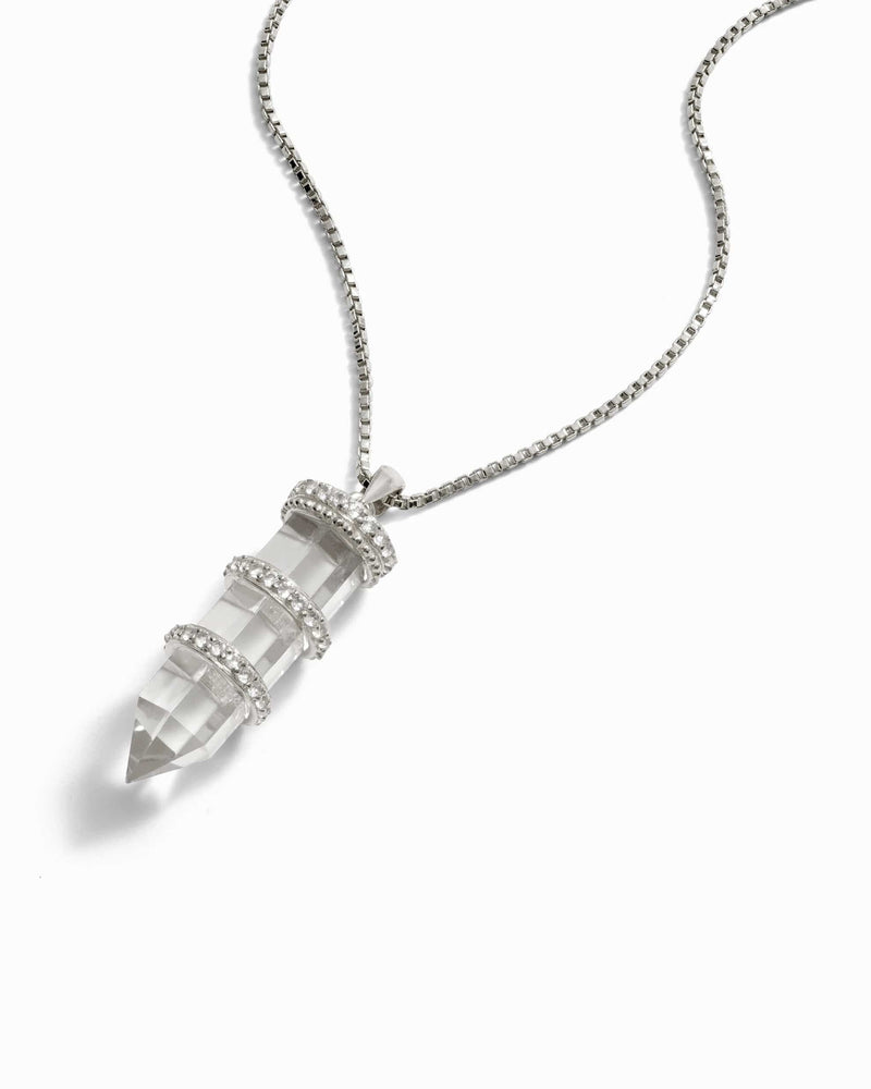 Awe Inspired's Manifestation Crystal Necklace, a silver chain adorned with a pointed clear quartz pendant featuring three silver bands, combines elegance and intention.