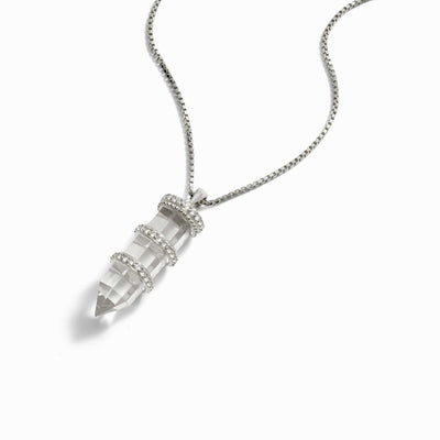 Awe Inspired's Manifestation Crystal Necklace, a silver chain adorned with a pointed clear quartz pendant featuring three silver bands, combines elegance and intention.