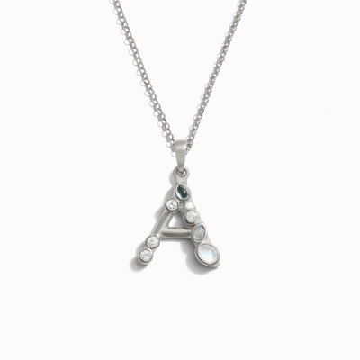 Awe Inspired's Silver Gemstone Initial Necklace features a pendant shaped like the letter "A," adorned with bezel set gemstones.