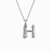 The Silver Gemstone Initial Necklace by Awe Inspired features a pendant in the shape of the letter "H," adorned with bezel set gemstones.