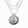 The Hunter's Moon Halo Necklace Set by Awe Inspired is a stunning silver necklace with three chains, featuring a prominent Artemis pendant that showcases an intricate relief of a person on horseback framed decoratively. This exquisite piece is crafted to absorb negative energy and impart an aura of protection to its wearer.