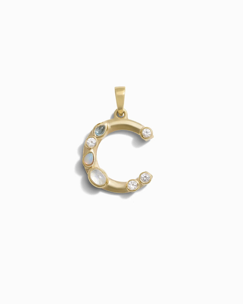 Awe Inspired's Gemstone Initial Pendant features a crescent moon adorned with bezel set gemstones, beautifully showcased on a plain white background.