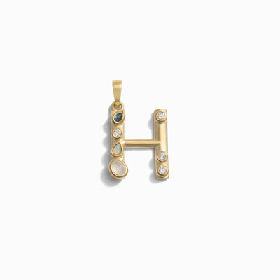 The Gemstone Initial Pendant by Awe Inspired, in the shape of the letter "H," is adorned with various bezel set gemstones including emeralds, opals, and diamonds—a perfect piece of personalized jewelry.