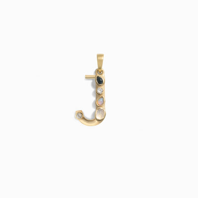 The Gemstone Initial Pendant by Awe Inspired is a gold pendant shaped like the letter "J," adorned with bezel-set gemstones including black onyx, moonstone, and diamond, displayed against a white background. This piece of personalized jewelry makes an exquisite addition to your collection.