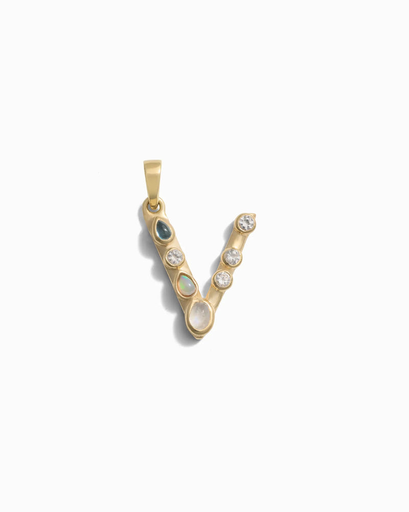 The Gemstone Initial Pendant by Awe Inspired is a gold letter 'V' pendant adorned with small bezel-set gemstones, perfect for those who love personalized jewelry.