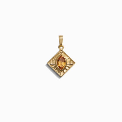 The Aura Pendant by Awe Inspired showcases a gold pendant with a diamond-shaped design and a teardrop-shaped amber gemstone in the center, exuding an aura of elegance.