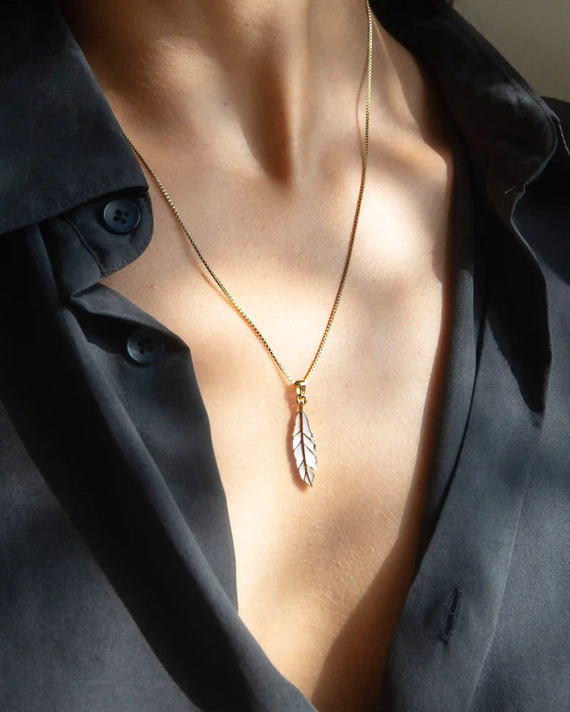 A person wearing a black shirt and the Awe Inspired Mother of Pearl Feather Amulet necklace.