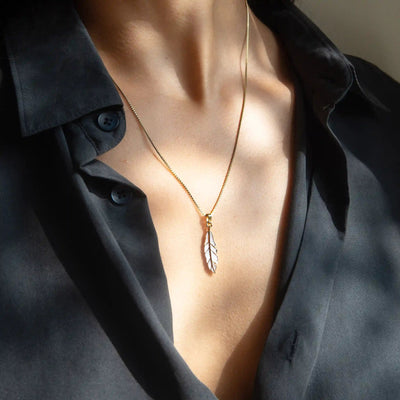 A person wearing a black shirt and the Awe Inspired Mother of Pearl Feather Amulet necklace.