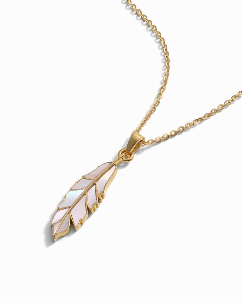 The Mother of Pearl Feather Amulet by Awe Inspired is a gold chain necklace featuring a pendant shaped like a feather with iridescent inlay on a white background, designed to invoke Athena's power.