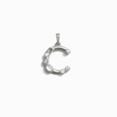 The Awe Inspired Gemstone Initial Pendant features a silver crescent-shaped design adorned with bezel set gemstones in both round and oval cuts, elegantly arranged along its curve.