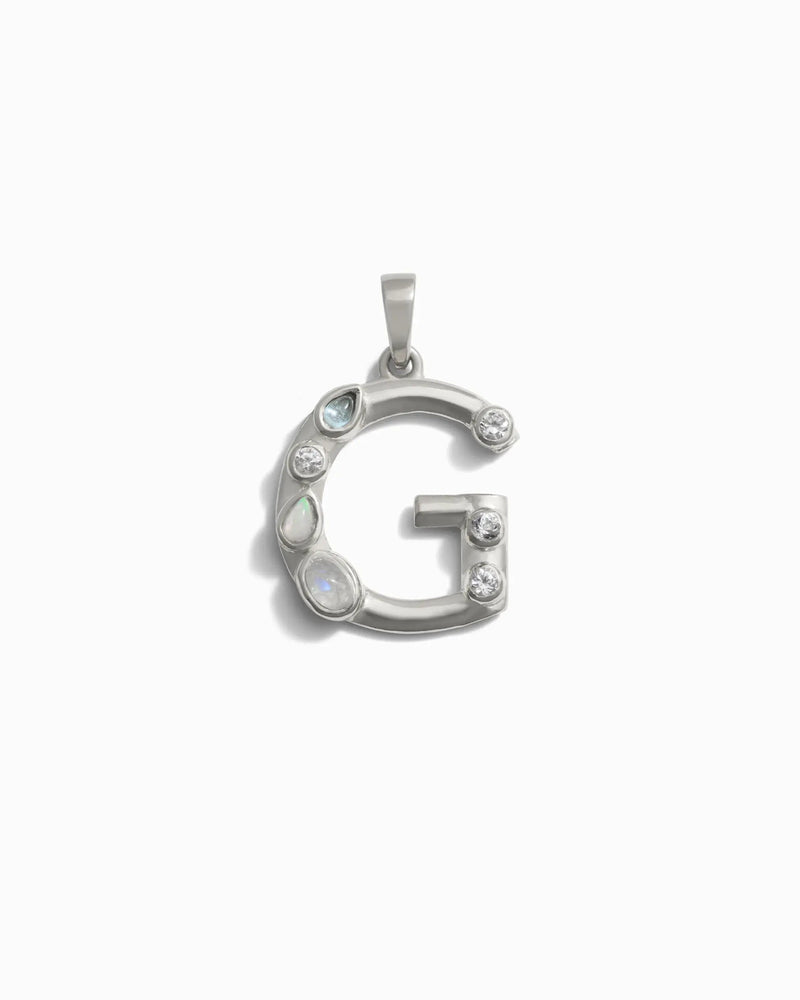 Awe Inspired's Gemstone Initial Pendant features a silver 'G' adorned with six bezel-set gemstones, artfully arranged along its curves.