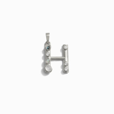 The Gemstone Initial Pendant by Awe Inspired is a charming piece of jewelry, designed as the letter "H" and adorned with small, bezel-set gemstones on a white background – perfect for those who appreciate personalized accessories.