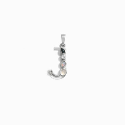 The Gemstone Initial Pendant by Awe Inspired is a silver pendant in the shape of the letter "J," adorned with five small, bezel-set gemstones in various colors.