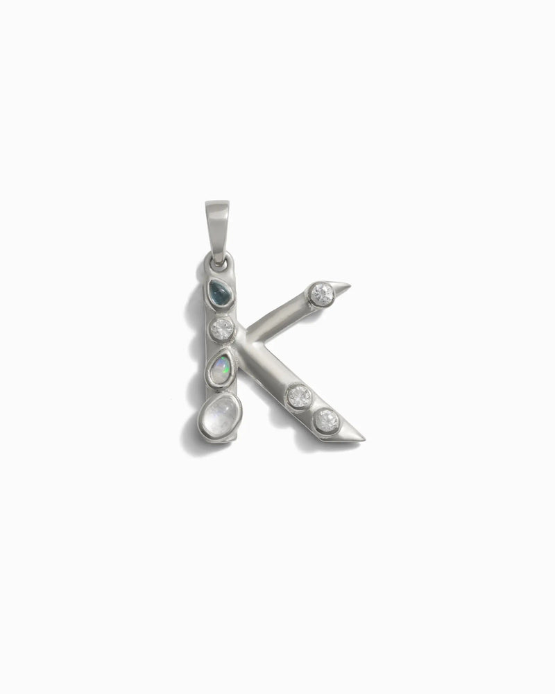Awe Inspired's Gemstone Initial Pendant, a silver "K" adorned with bezel set gemstones on a white background.
