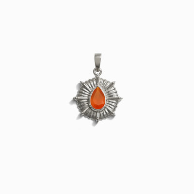 The Aura Pendant by Awe Inspired is a silver pendant with a sunburst design, featuring an orange teardrop-shaped center that is believed to enhance your aura and balance your chakra.