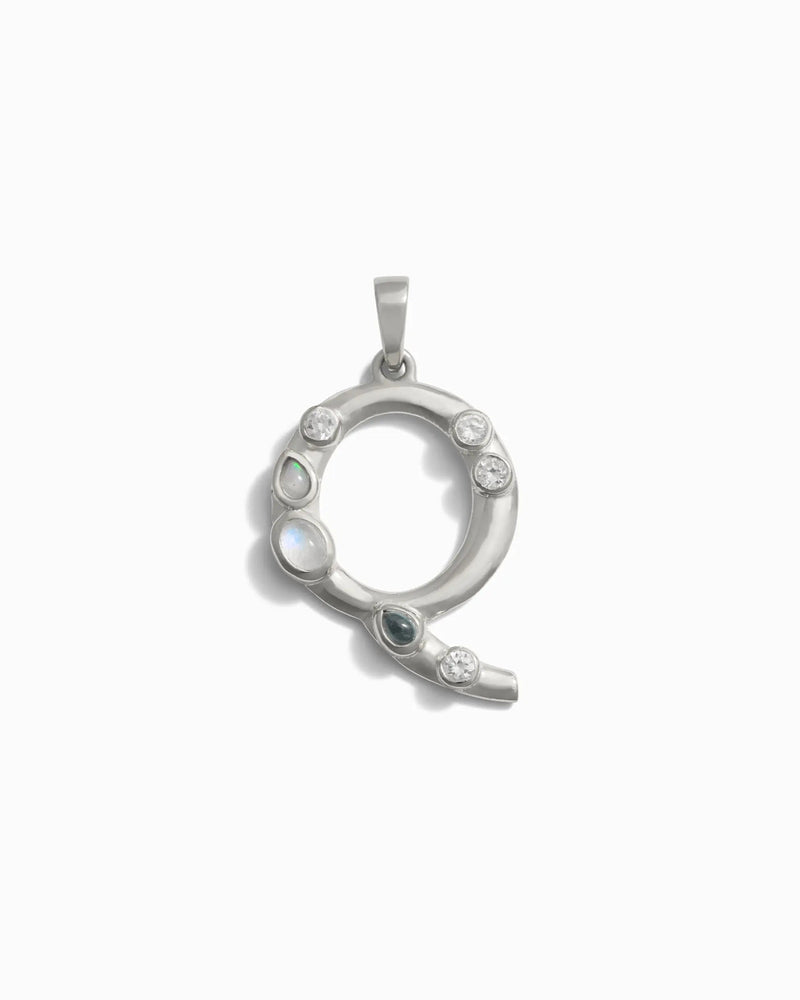The Awe Inspired Gemstone Initial Pendant, shaped like the letter "Q" and adorned with bezel set gemstones, features small round and teardrop-shaped stones. This distinctive piece of personalized jewelry makes for a unique initial charm.