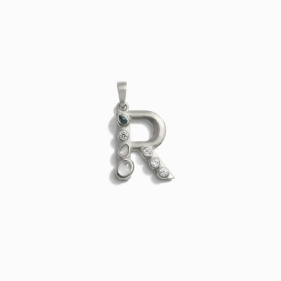 The Gemstone Initial Pendant by Awe Inspired is a silver pendant shaped like the letter R, adorned with multiple small bezel set gemstones along one side, making it ideal for personalized jewelry.