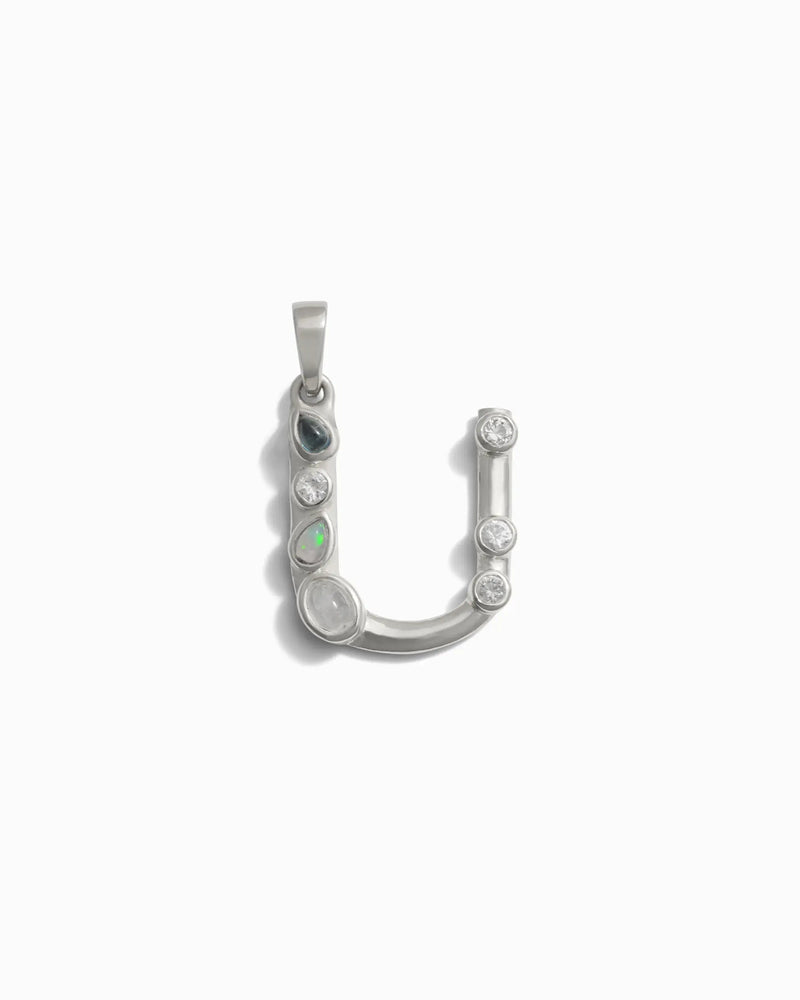 Awe Inspired's Gemstone Initial Pendant features a silver "U"-shaped design adorned with five bezel set gemstones of varying sizes, beautifully set against a white background.