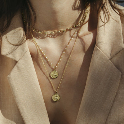 A woman wearing a tan jacket and an Awe Inspired Hera Pendant.