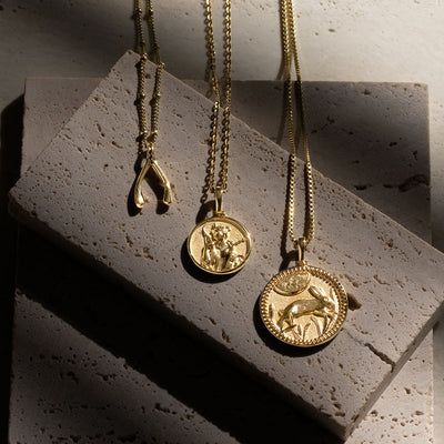Three Awe Inspired Artemis Pendant necklaces sitting on top of a stone.